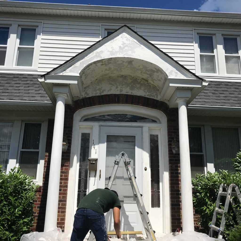 The before look of a house, with a man working on renovations, depicting its appearance prior to any changes or enhancements